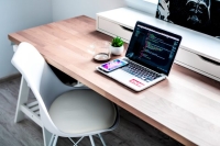 Office desk with laptop on with coding on screen